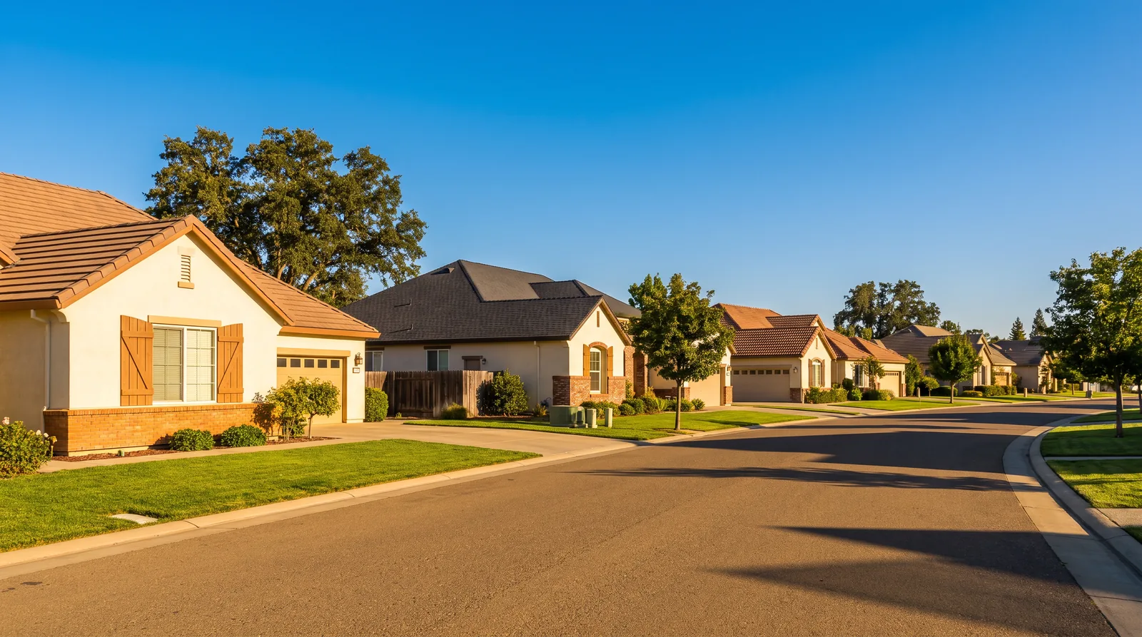 Suburban Sacramento Valley neighborhood street lined with homes under a clear afternoon sky